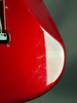 Close-up of a red guitar with white pickguard on a dark background