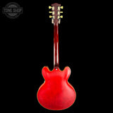 A red electric guitar shown from the back against a solid black background, with a Tone Shop watermark in the top left corner.