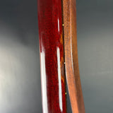 Close-up of a glossy dark red wood instrument body panel next to a natural brown wood edge, showing wood grain and a reflective finish against a dark gray background.