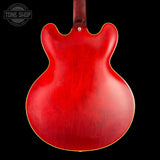 The back of a red electric guitar with a glossy finish, shown against a solid black background. A Tone Shop watermark is visible in the top-left corner.