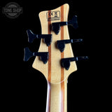 Close-up of a guitar headstock with tuning pegs on a black background, featuring the Tone Shop logo.