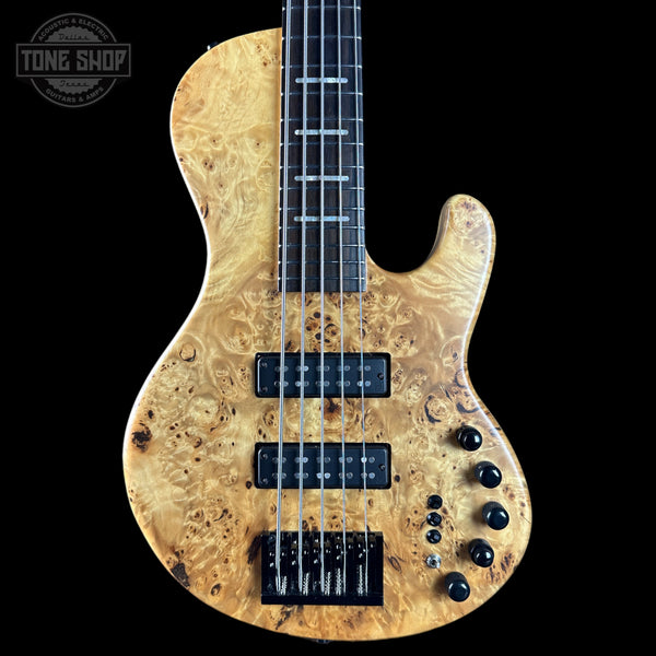 Wooden electric bass guitar with a black background, featuring the Tone Shop logo.