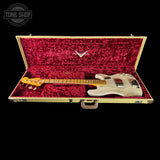A light natural wood four-string bass guitar displayed inside an open hard case with a bright red plush lining, set against a solid black background.