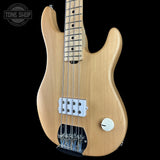 Electric bass guitar with a natural wood finish on a black background, featuring the Tone Shop logo.