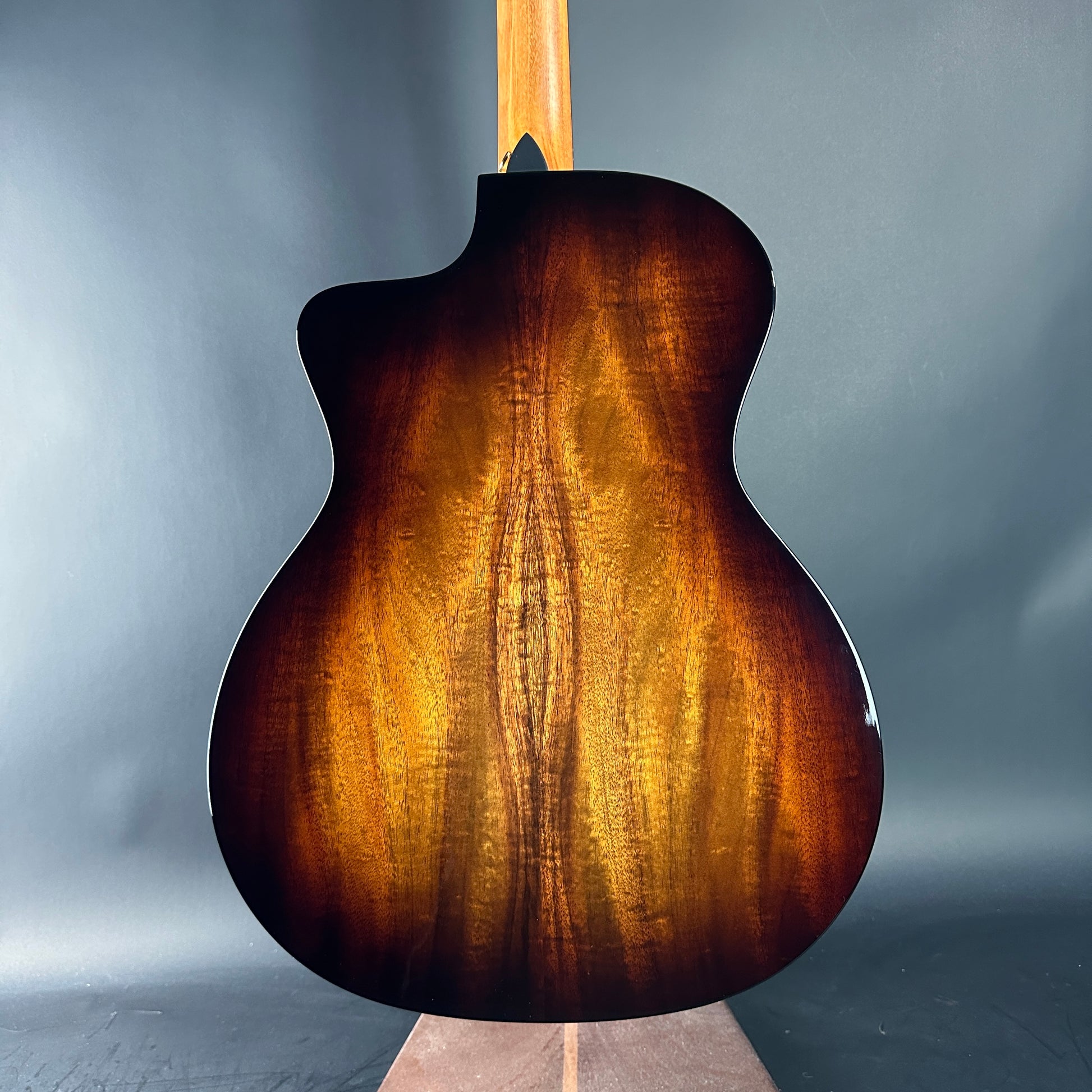 Back view of a brown acoustic guitar on a gray background