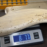 A close-up of a light natural wood guitar body resting on a digital scale displaying 8.77 lbs, with part of an orange-yellow headstock and neck visible at the top.