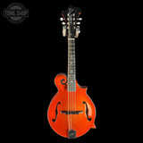 An orange mandolin with a glossy finish, black headstock, and black neck, shown against a solid black background with a Tone Shop watermark in the top left corner.