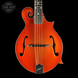 An electric mandolin with a vibrant orange metallic finish, shown from the front against a solid black background. The mandolin features a distinctive scroll-shaped body, two f-holes, six strings, and a black headstock with a visible 'Gibson' logo.