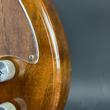 Close-up of a wooden guitar with a clear finish on a dark background