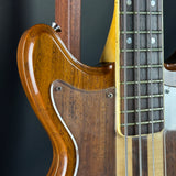 Close-up of a wooden electric bass guitar with a dark background
