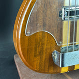 Close-up of a wooden electric bass guitar on a dark background