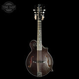 A dark brown glitter-finish mandolin with a glossy finish, shown vertically against a solid black background. A Tone Shop watermark is visible in the top-left corner.