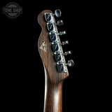 Close-up of a guitar headstock with tuning pegs on a black background, featuring the Tone Shop logo.