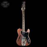 Wooden electric guitar with a black pickguard on a white background, featuring the Tone Shop logo.