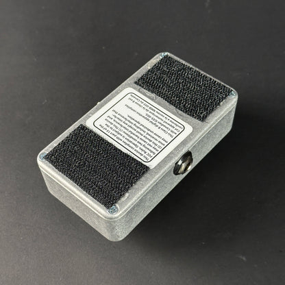 Small rectangular device with black foam pads on a dark background
