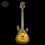 A double-cutaway electric guitar with a vibrant yellow and brown tiger stripe wood finish, shown against a solid black background. The guitar features white hardware, a dark fretboard with gold inlays, and a headstock with six tuning pegs.