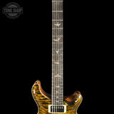 Close-up of an electric guitar neck and lower body against a black background, showing a glossy brown and amber flame maple finish, dark fretboard, and bird inlays. A Tone Shop watermark is visible in the upper left.