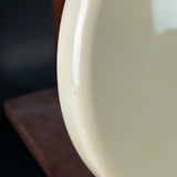 Close-up of a light beige ceramic plate on a dark surface