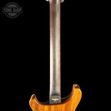 Close-up of the back of an electric guitar showing the back body and neck against a solid black background, with a Tone Shop watermark in the top left corner.