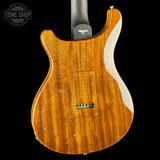 The back of an electric guitar with a glossy natural wood finish, showing the grain pattern and a white side stripe, photographed against a solid black background.