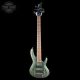 Green electric bass guitar on a black background with 'Tone Shop' logo.