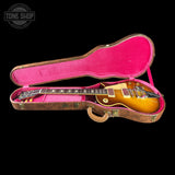 A gold-finish electric guitar resting inside an open pink-lined hard case on a black background, with a Tone Shop watermark in the top left corner.