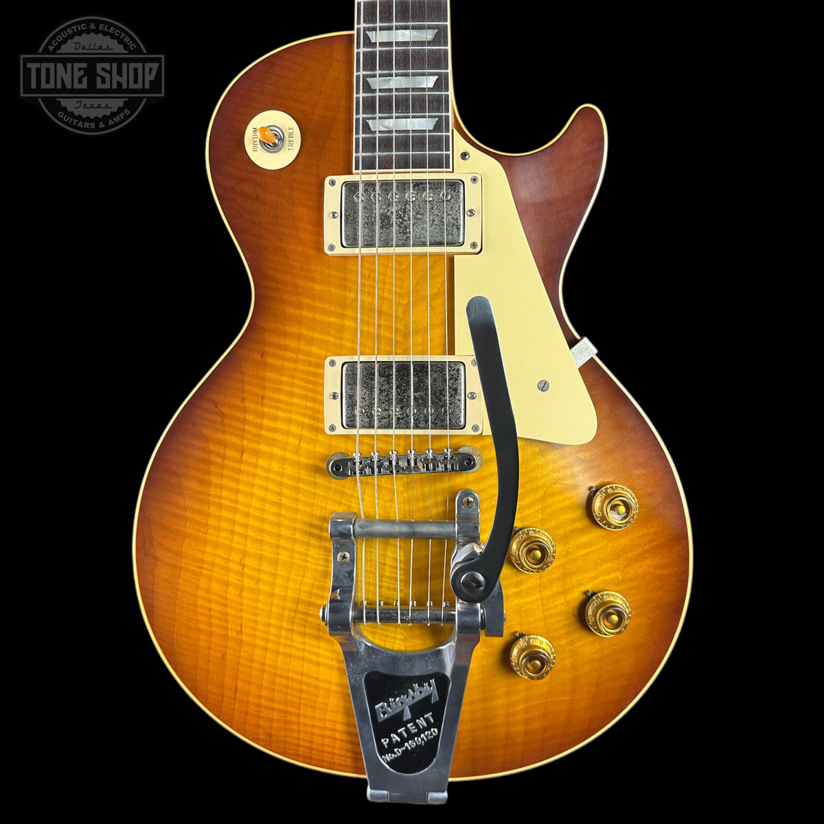 A Gibson Les Paul Custom electric guitar with a vibrant sunburst finish, featuring a gold-toned body, cream pickguard, chrome hardware, and a black Leslie speaker mount, shown against a solid black background.