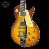 A Les Paul style electric guitar with a sunburst finish, featuring a cream pickguard, gold-toned hardware, and a black Leslie speaker mount, shown against a black background.