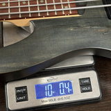 Digital scale displaying weight of a guitar neck on a wooden surface