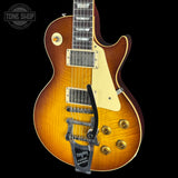 A classic electric guitar with a sunburst finish, featuring a gold-toned body, cream pickguard, and a black tailpiece, shown against a solid black background.