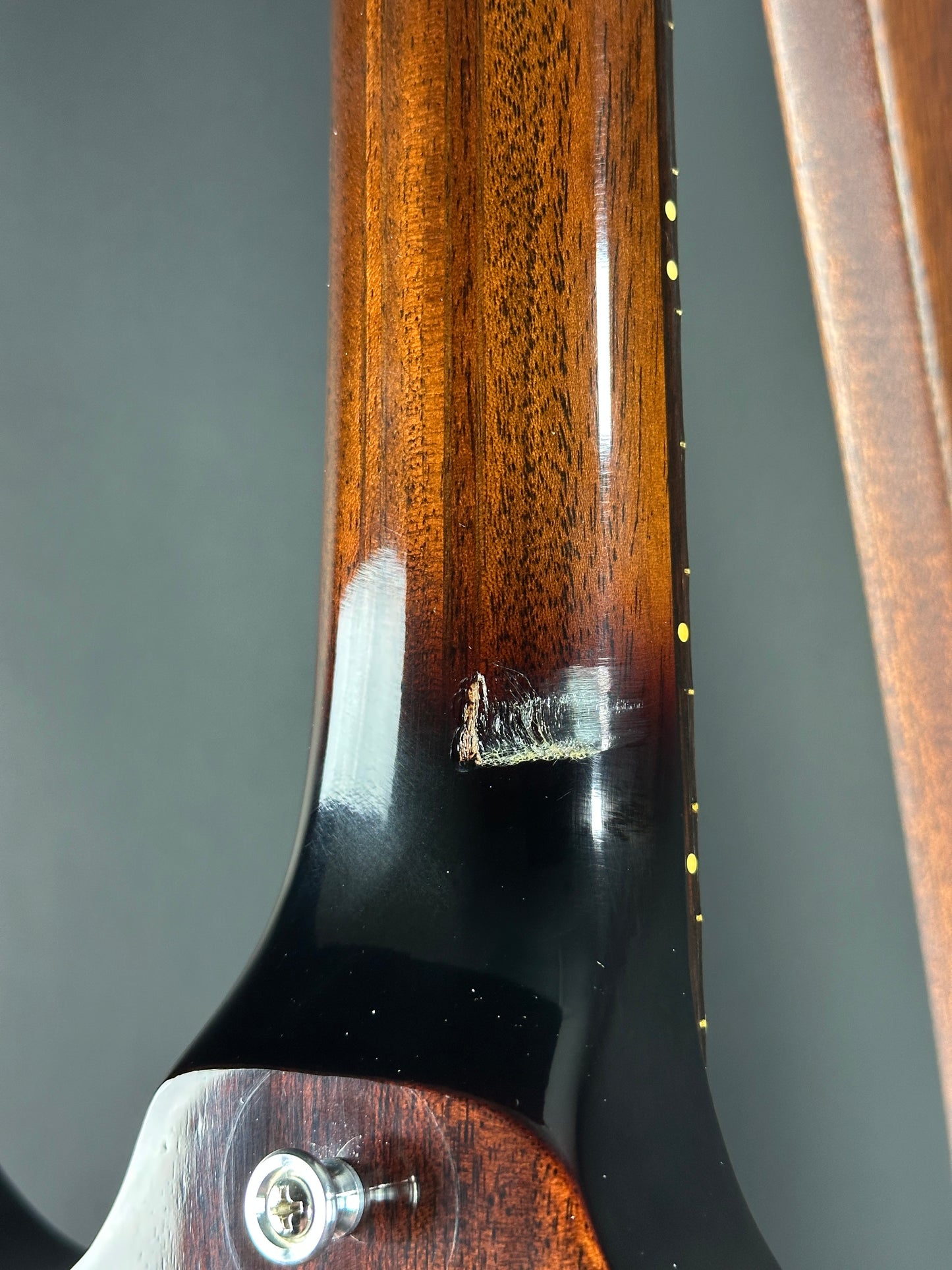Close-up of a guitar neck with a visible scratch on the black surface.