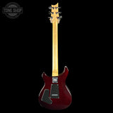 Red electric guitar with a visible brand logo on a black background