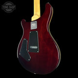 Red electric guitar with a PRS logo on a black background