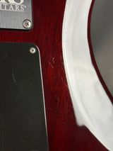 Close-up of a guitar with a brand label on a wooden surface