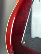 Close-up of a guitar's body with a red finish and visible wood grain.