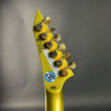 Gold guitar headstock with tuning pegs on a gray background