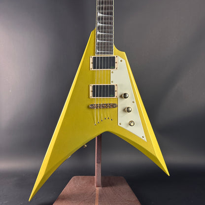 Yellow electric guitar on a stand against a dark background
