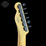 Close-up of a guitar neck with tuning pegs on a black background, featuring the Tone Shop logo.