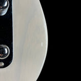 Close-up of a guitar neck with white pickguard and black hardware on a black background