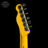 Close-up of the headstock of a yellow-finish electric guitar against a black background, showing six tuning pegs and a Tone Shop watermark in the upper left corner.