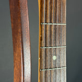 Close-up of a guitar neck with frets and strings on a gray background
