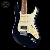 Black electric guitar with a white pickguard on a black background, featuring the Tone Shop logo.