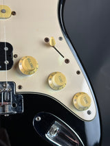 Close-up of a guitar's control knobs with a focus on the 'Volume' and 'Tone' knobs.