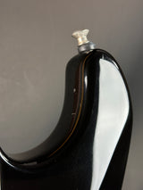 Close-up of a black and white ceramic object with a metallic cap on a gray background