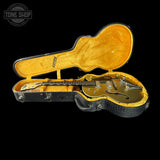 Gold electric guitar in an open case with 'Tone Shop' logo.