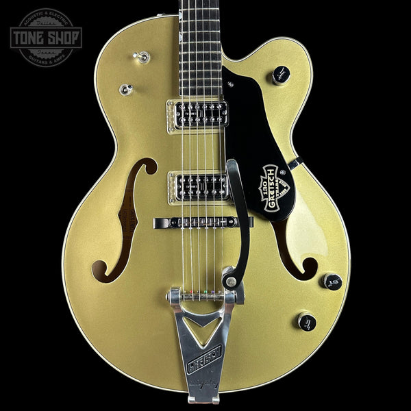 Gold electric guitar with a black pickguard on a black background, featuring the Gretsch logo.