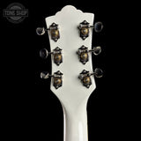 Close-up of a white guitar headstock with tuning pegs on a black background, featuring the Tone Shop logo.
