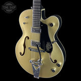 Gold electric guitar with a black pickguard on a black background, featuring the Gretsch logo.