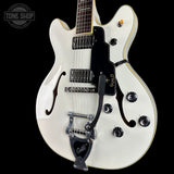 White electric guitar with black accents on a black background, featuring the Guild logo.