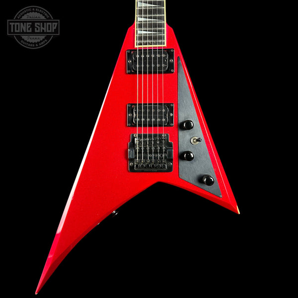 A red electric guitar with a black pickguard and black hardware, shown from a front-three-quarter angle against a solid black background. A Tone Shop watermark is visible in the top-left corner.